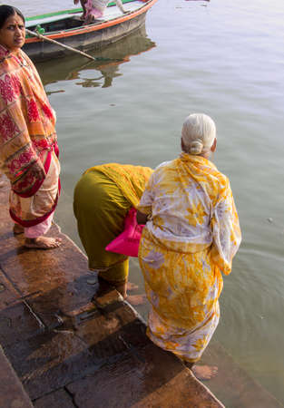 women in colorful saries taking a holy bath in the waters of the holy river Gangesのeditorial素材