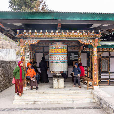 A big prayer wheel in front of a drug store in Thimpu  People are sitting, waiting for their drugs, and turning the wheel のeditorial素材