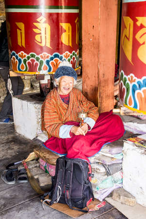 A bhutanese man is sitting at the prayer wheel of the national memorial chorten of Thimpu, Bhutan  Thimpu is the capital of Bhutan のeditorial素材
