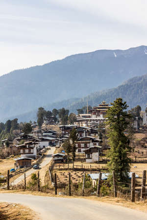 A view over rinchen gang village, Phobjika valley, Bhutan  The monastery is recognizable by the golden, multiple roof  In the background are the mountainsの写真素材