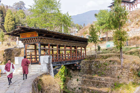 The bridge leading to the beautiful dzong of Trongsa, Bhutan  Men in traditional costumes are walking over it  Dzongs are fortress like buildings that house a monastery and administration offices のeditorial素材