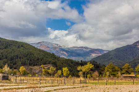 The beautiful view to the mountains in Bhutan  In the foreground are fields and fruit trees  の写真素材