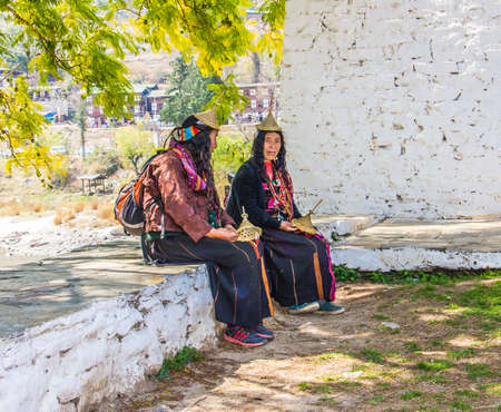 Two nomad woman are sitting outside the dzong of Punakha,  Bhutan, trying to sell hats  They are wearing the typical nomad costume のeditorial素材