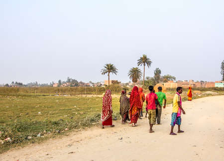 Nepali farmers in the outskirts of janakpur, nepal, are walking home from fieldwork  They are dressed in colorful clothes のeditorial素材
