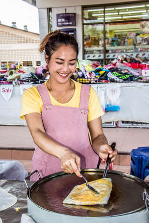 A beautiful young woman is preparing delicious food on the main street of fishing in the north of Thailandのeditorial素材