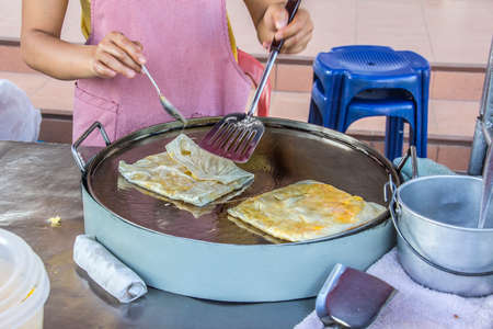 A beautiful young woman is preparing delicious food on the main street of fishing in the north of Thailandの写真素材