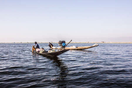 A fisherman at Inle lake is catching fish with a net .のeditorial素材