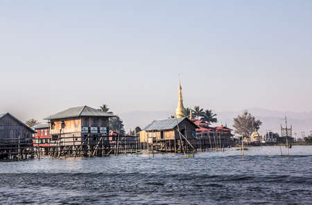 stilthouse village with a golden Paya Pagoda at Inle lake Myanmarのeditorial素材