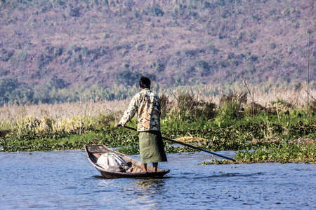 A woman at Inle lake is coming from the market with the goods she  bought in her boat.のeditorial素材