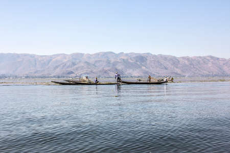 A legrowing fisherman at Inle lake is catching fish with a net . のeditorial素材