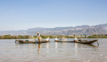 A legrowing fisherman at Inle lake is catching fish with a net .のeditorial素材