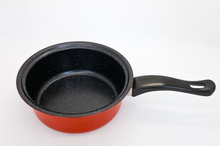 Black and red non-stick pan for cooking in the kitchen, pan for cooking vegetables and cooking water for household needs, isolated on whiteの写真素材