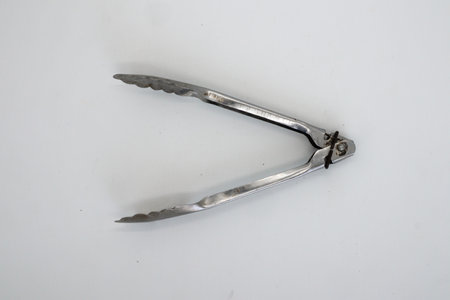 Tongs or frying pan made of stainless isolated on whiteの写真素材