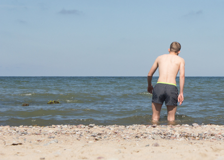 a young man walks into the seaの写真素材
