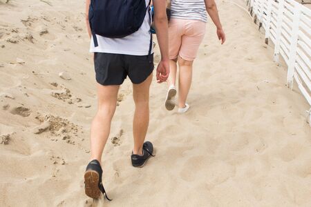 girl and boy walking along in the sand on the beachのeditorial素材