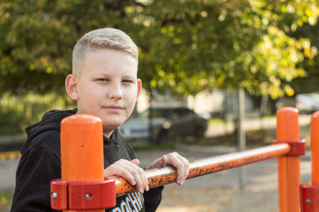the young man in theme jacket with blond hair standing on the Playgroundの写真素材