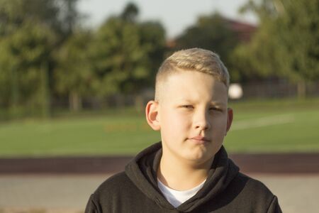 the young man in theme jacket with blond hair standing on the Playgroundの写真素材