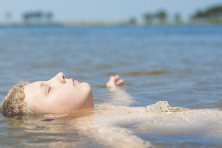 A boy swimming in blue waterの写真素材