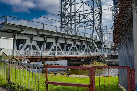 iron trestle drawbridge stands over the river against the blue skyの写真素材