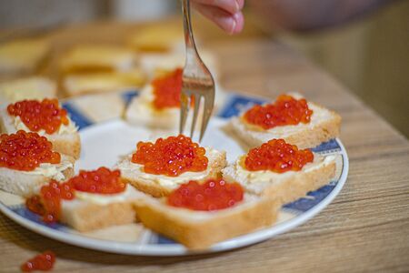 sandwiches with red caviar are on a plate on a wooden tableの写真素材