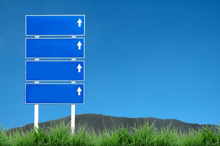 roadsign with green grass and blue skyの写真素材