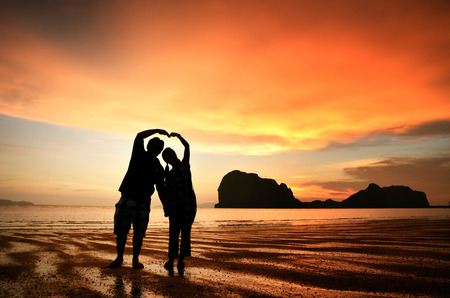 Romantic couple holding hands at sunset on the beachの写真素材