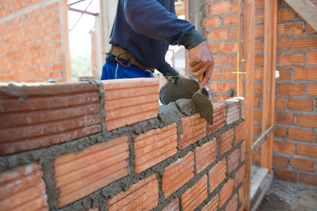 Worker building masonry house wall with bricksの写真素材