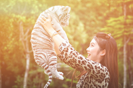 pretty women hold baby white bengal tiger with flare lightの写真素材