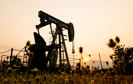 pumpjack at an oil drilling site and sunsetの写真素材