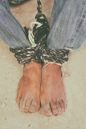 hopeless man feet tied together with rope, human traffickingの写真素材
