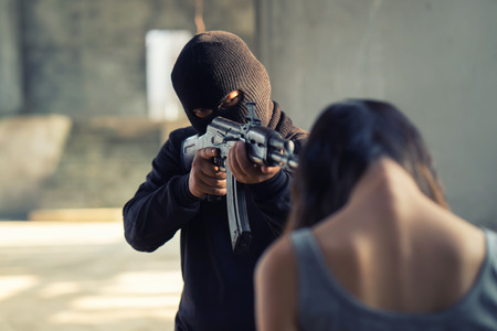 Man in balaclava threatening with gun to woman abductedの写真素材