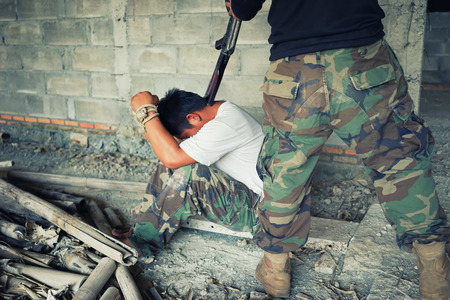 Terrorist in balaclava threatening with gun to man abductedの写真素材