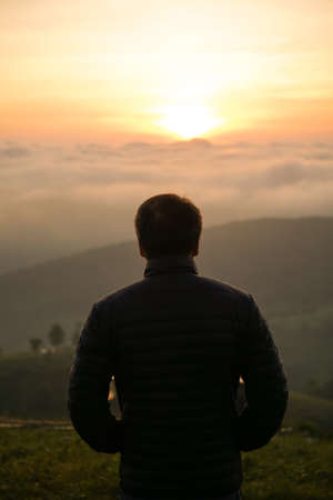 man watching sunrise alone at hilltopの写真素材