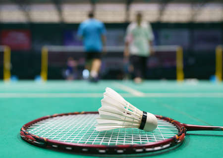 shuttlecock on green badminton playing court with player in backgroundの写真素材