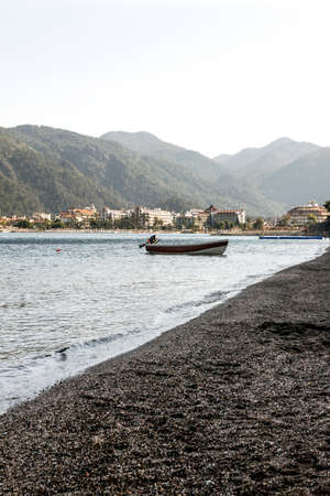 white boat near the shore in water with mountains in backroundの写真素材