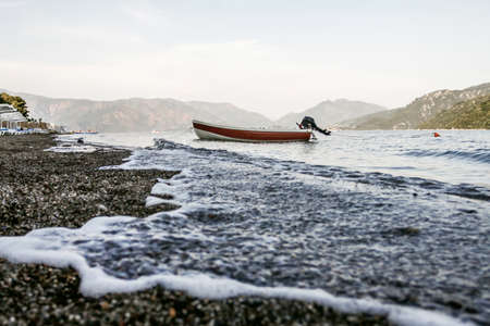 white boat near the shore in water with mountains in backroundの写真素材