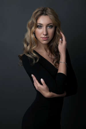 portrait of beautiful woman in black dress standing on dark backgroundの写真素材