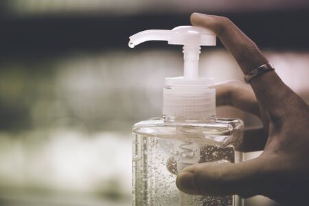 Hand pushing / pressing sanitizer hand gel bottle by index finger that contain alcohol gel dripping at the tip. Concept healthcare for protect virus Covid-19の写真素材