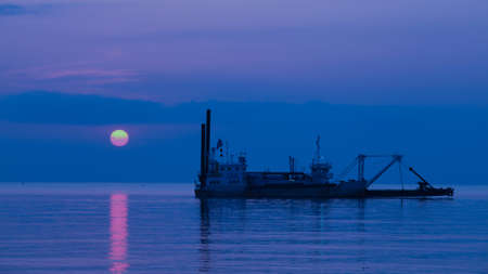 Sandsuck boat working in the sea. beautiful sunriseの写真素材