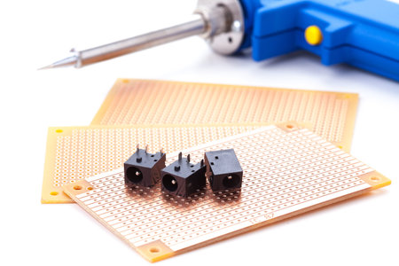 power jack female placed on the pcb. Electronic printed board. Soldering iron is background