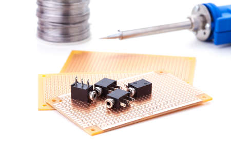 audio jack female placed on the pcb. Electronic printed board. Soldering iron is backgroundの写真素材