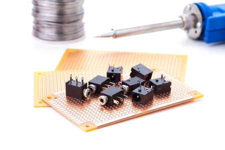 audio jack female placed on the pcb. Electronic printed board. Soldering iron is backgroundの写真素材