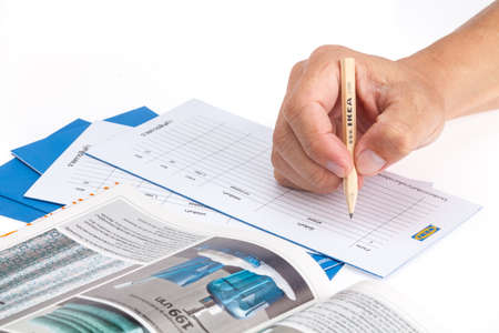 SONGKHLA THAILAND - JANUARY 27, 2015: Man 's hand holding a pencil to write an IKEA shopping list . IKEA Founded in Sweden in 1943, Ikea is the world's largest furniture retailer.のeditorial素材