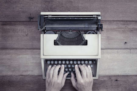 Human hand on vintage type writer wich place on wooden table.の写真素材