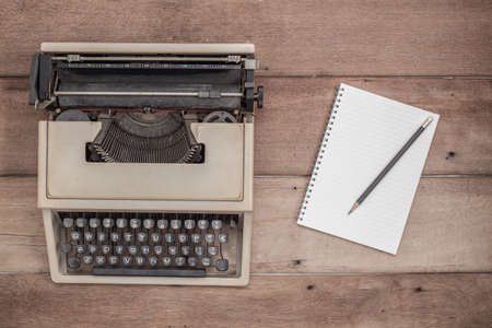 Vintage typewriter and notebook place on wooden table.の写真素材