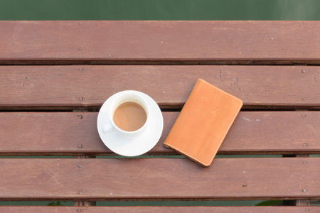 Coffee cup and notebook place on wood terraceの写真素材
