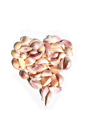 Lots of Garlic cloves are arranged as a heart-shaped,Spices and herbs are spicy on white backgroundの写真素材