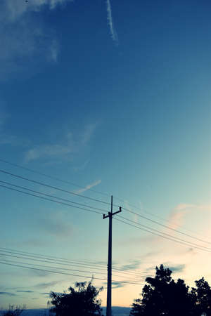 Electricity poles at the roadside with beautiful blue sky before sunset,Photos back-light at the horizon began to turn orangeの写真素材