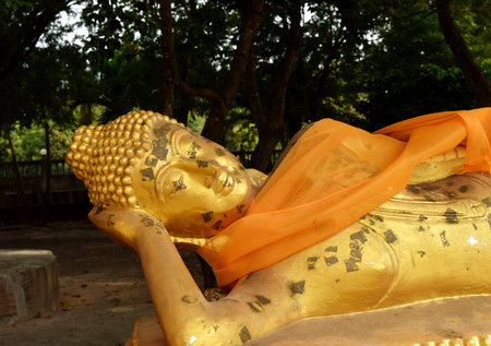 Reclining Buddha gold statue clothed yellow robe at Buddhist  templeの写真素材