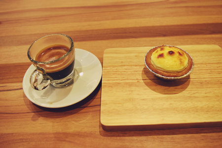 Cheese Tart on  wooden tray and Coffee espresso in transparent glass on brown table